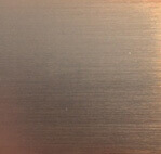 Brushed metal texture displaying a gradient from dusty rose to brownish-grey, with subtle horizontal striations and a dull champagne tone.